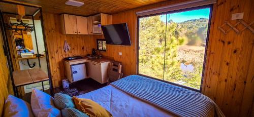 a room with a bed and a large window at ANC MONTANHA - 8min do capivari in Campos do Jordão
