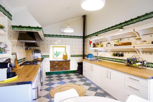 a kitchen with white cabinets and a checkered floor at Nature Tourism Quinta Nova in Castanheira de Pêra