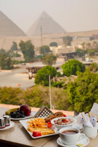Una mesa con platos de comida y una vista de las pirámides. en Turquoise Pyramids & Grand Egyptian museum view Hotel, en El Cairo