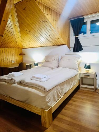 a large bed in a room with a wooden ceiling at La Petite Maline friends & family in Sierre