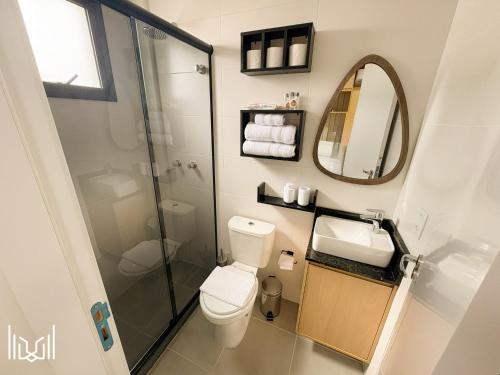 a bathroom with a toilet and a sink and a mirror at Apartamento Central próximo ao Jardim Botânico, Shopping Estação e UFPR in Curitiba