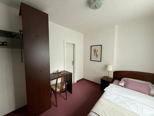 a bedroom with a bed and a desk and a bed at Hotel-Pension KAMÝK in Prague