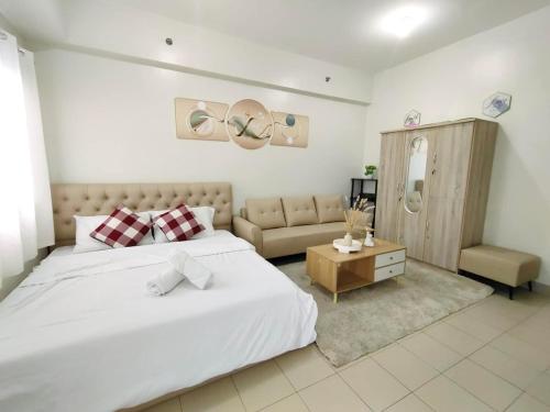 a bedroom with a large white bed and a couch at Hill Residence by Sarah Rentals in Manila