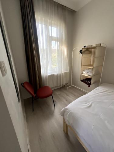 ein Schlafzimmer mit einem Bett und einem roten Stuhl neben einem Fenster in der Unterkunft Şişli Suites - Room31 in Istanbul