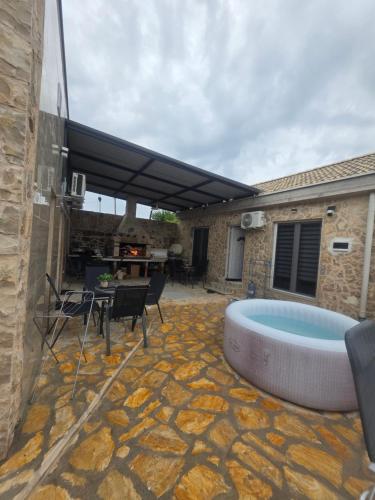a patio with a hot tub and a table and chairs at App 3 Ville Adan in Donji Zemunik