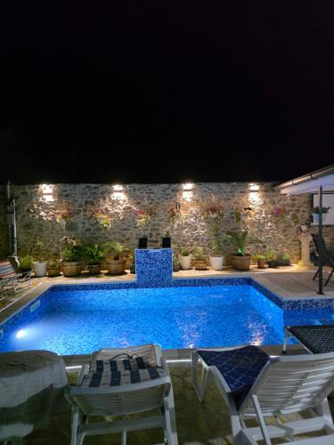 a swimming pool at night with chairs and a table at App 3 Ville Adan in Donji Zemunik