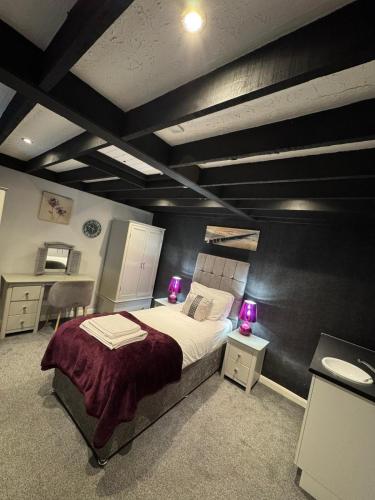 a bedroom with a large bed with two purple lamps at Watton Vibe Hotel in Watton