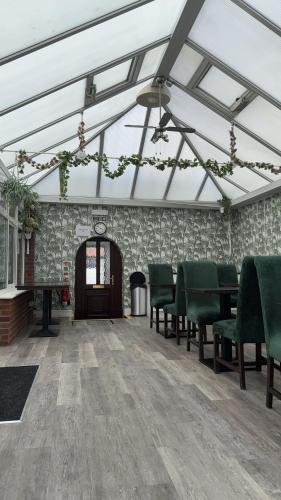 an empty room with green chairs and a table at Watton Vibe Hotel in Watton
