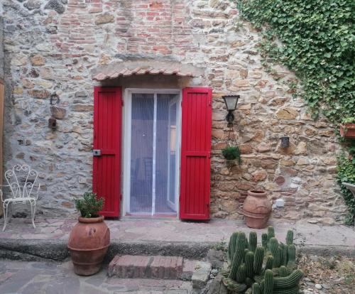 a red door of a stone building with cactus at Casa Belvedere in Suvereto
