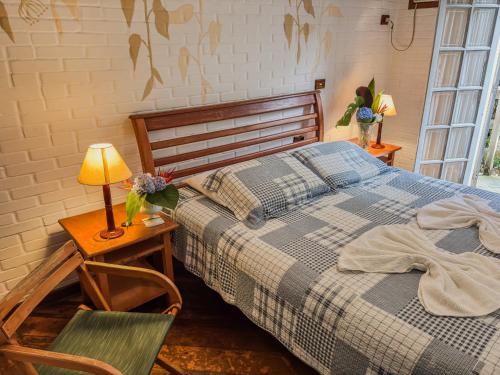 a bedroom with a bed and a table with a lamp at Recanto Quinta da Jade in Itaipava