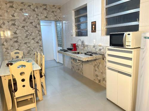 a kitchen with a sink and a table with chairs at Aconchego e comodidade no coração da cidade in Nova Friburgo