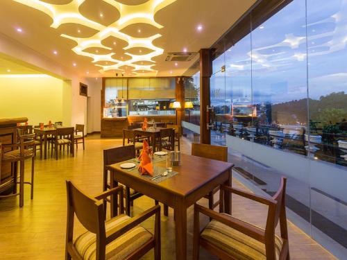 restauracja ze stołami i krzesłami oraz dużym oknem w obiekcie Heaven Seven Kandy w mieście Kandy