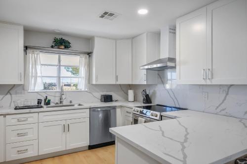 a white kitchen with white cabinets and a window at NEW! Vegas Pool Paradise, 4BR, BBQ, Sleeps 14 in Las Vegas