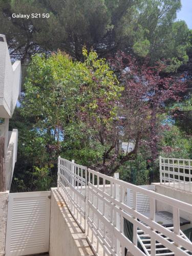 a white fence in front of some trees at Studio 5 min des plages et cœur de ville in La Grande-Motte