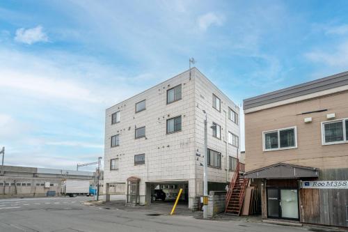 a white brick building with a staircase in front of a building at Silk Coat 403 - Vacation STAY 19404 in Chitose