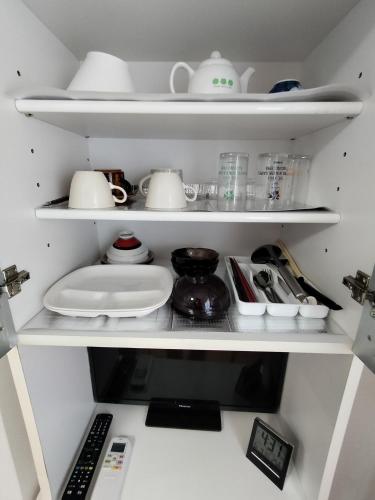 a kitchen shelf filled with dishes and other kitchen items at Guesthouse Mulberry Kagoshima- Vacation STAY 50746v in Kagoshima