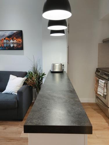 a kitchen with a black counter top and a couch at Chalet Tranquillité Orford in Magog-Orford