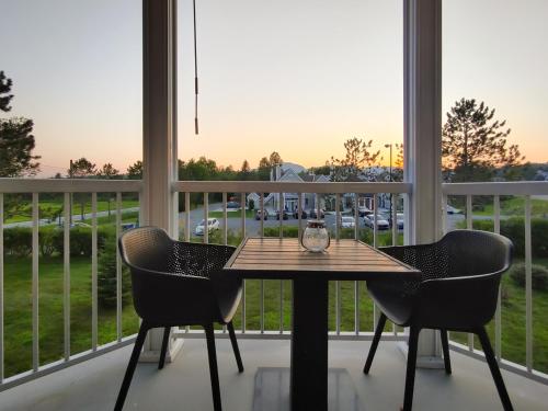 a table and chairs on a balcony with a view of a parking lot at Chalet Tranquillité Orford in Magog-Orford
