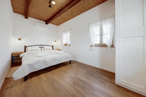 a white bedroom with a bed and a wooden floor at Rustique 1952 in Šiljakovina