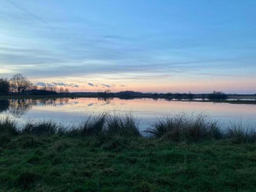 a view of a lake with the sunset in the background at Bungalow in Haaksbergen near Nature Trails in Haaksbergen