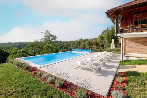 a swimming pool with lounge chairs next to a house at Rustique 1952 in Šiljakovina