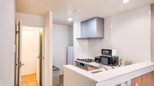 Una cocina blanca con estufa y fregadero. en Little Planet - Vacation STAY 19452, en Osaka