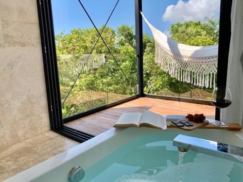 普拉亚卡门GLASS JUNGLE VILLA with amazing green views -10 min DT的带浴缸、书籍和窗户的浴室