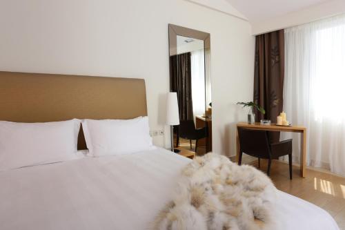 a bedroom with a white bed with a desk and a desk at Chloe Luxury Hotel in Kastoria
