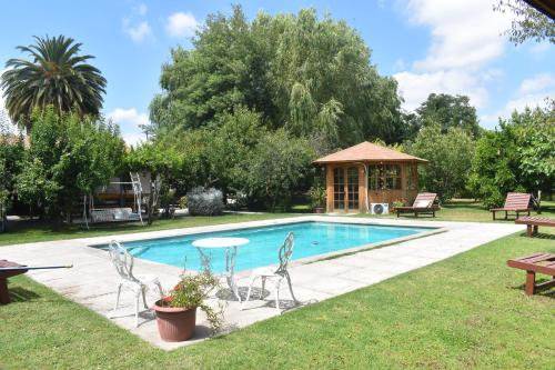 a swimming pool with chairs and a gazebo at Hostal Pando in Santa Cruz