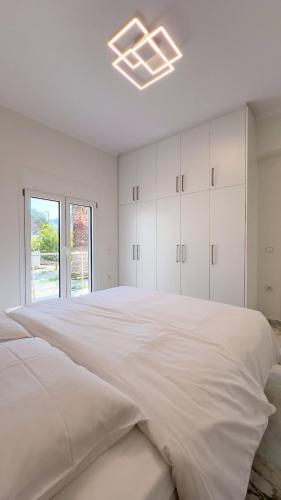 a white bedroom with a large bed and a window at Variea Vista in Mytilene