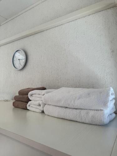 a shelf with towels and a clock on a wall at Hotel Restaurant Sjor Luka Turanj in Turanj