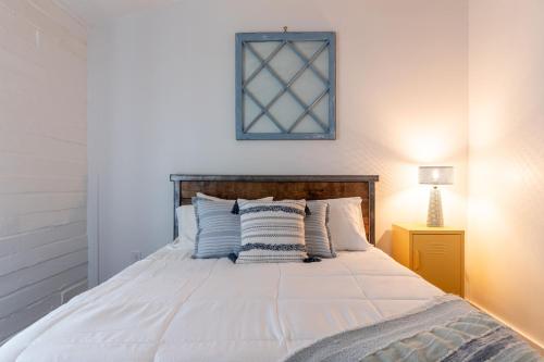 a bedroom with a white bed with a picture on the wall at Tranquility Pond Cabin - Nature Retreat on 5 Acres in Buford