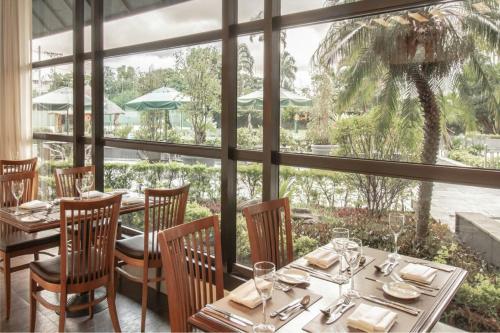 a dining room with tables and chairs and a large window at Marriott São Paulo Airport Hotel in Guarulhos