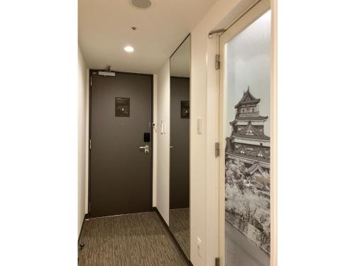 a hallway with a door with a painting on the wall at Smile Hotel Hiroshima - Vacation STAY 77672v in Hiroshima