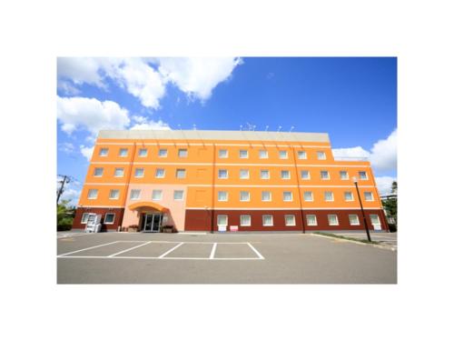 a large orange building with a parking lot at Smile Hotel Sendai Izumi Inter - Vacation STAY 77951v in Sendai