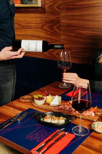 a person pouring a glass of wine on a table at Courtyard by Marriott Brno in Brno