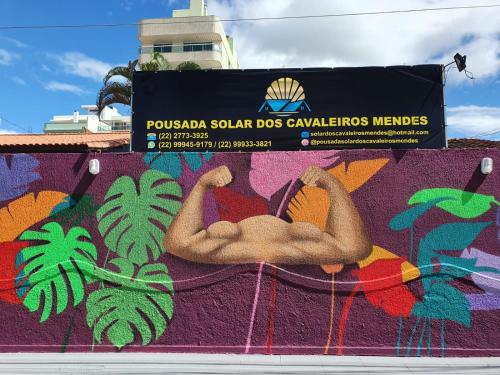 a sign on a wall with a painting of a man at Pousada Solar dos Cavaleiros Mendes in Macaé