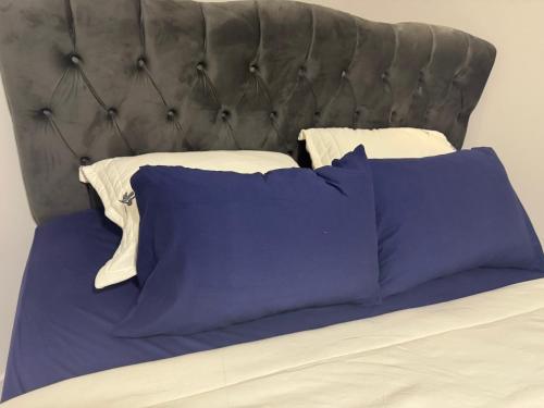 ein Bett mit lila Kissen und einem grauen Kopfteil in der Unterkunft Apartamento aconchegante in Baixo Guandu