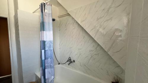 a bathroom with a shower and a white marble wall at Ferienwohnung Harzgebirge in Goslar