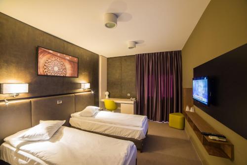 Habitación de hotel con 2 camas y TV de pantalla plana. en Hotel Lux Divina en Brasov