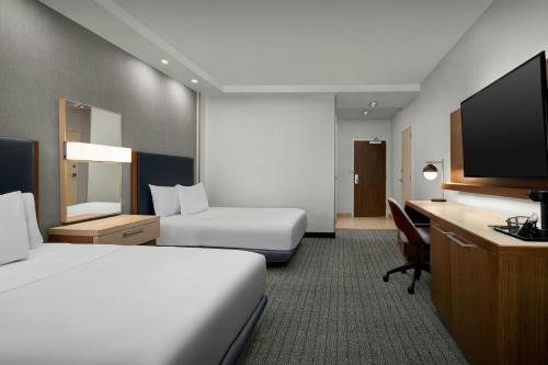 a hotel room with a bed and a desk and a tv at Courtyard by Marriott Atlanta Kennesaw in Kennesaw