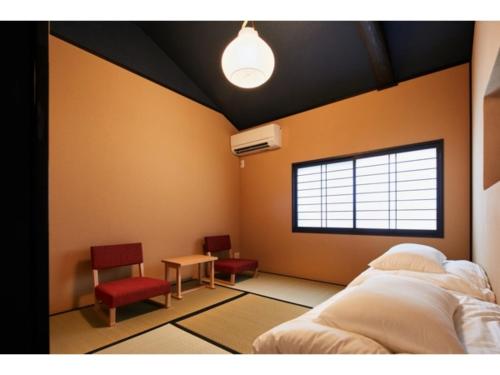 a bedroom with a bed and two chairs and a window at TSUBOMI luxury Inn Shimabara Bettei 1 - Vacation STAY 83230v in Kyoto