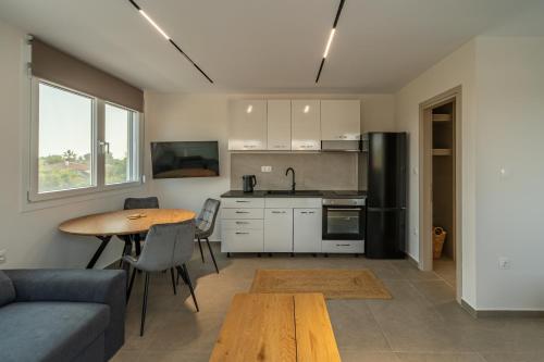 a kitchen and living room with a table and a couch at Elonea Villas, Luxury Villas and Studios in Kallikrateia Halkidiki with Garden, Veranda & BBQ in Nea Kalikratia