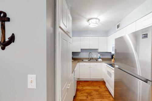 a kitchen with white cabinets and a stainless steel refrigerator at Turn of River 4F in Folly Beach