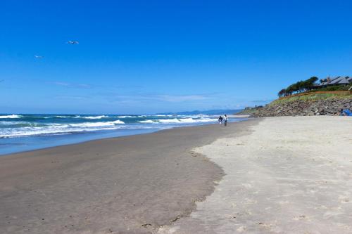 two people walking on a beach near the ocean at Pacific Sands Resort #22 in Neskowin