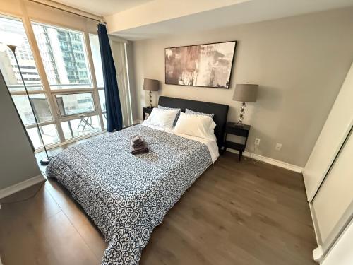 ein Schlafzimmer mit einem Bett und einem großen Fenster in der Unterkunft Large Downtown 2Br condo with Parking steps to Eaton Centre, UofT and SickKids in Toronto
