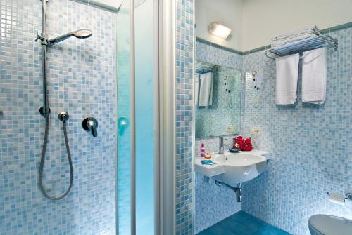a blue tiled bathroom with a shower and a sink at Hotel Lido in Gabicce Mare