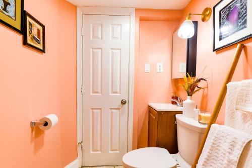 an orange bathroom with a toilet and a sink at 7even Clouds Éclair- Cozy basement nest near NE DC in Hyattsville