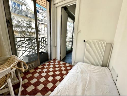 a small room with a bed and a window at Stylish studio 3-4p with AC and balcony near Champs-Élysées in Paris