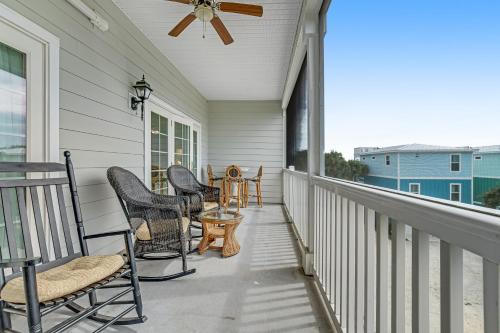 a porch with chairs and a table and a ceiling fan at Marsh Winds 2K in Folly Beach
